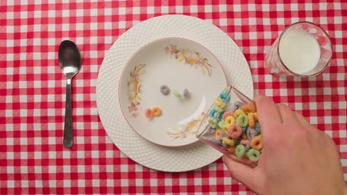 Colorful Round Flakes Fall Into the Plate and are Filled with Milk