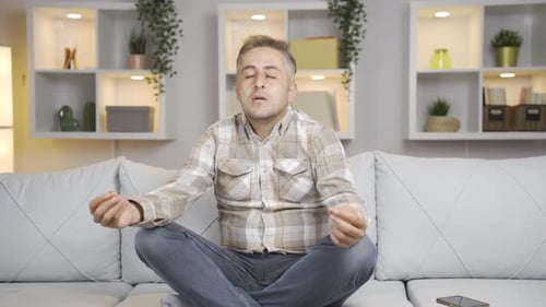 Man Meditating on Couch in Living Room