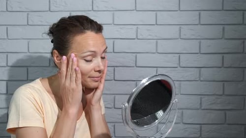 Woman Applies Facial Cream in Front of Mirror