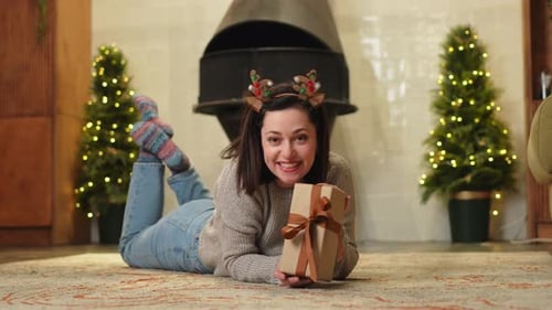 Woman lies on floor with Christmas present