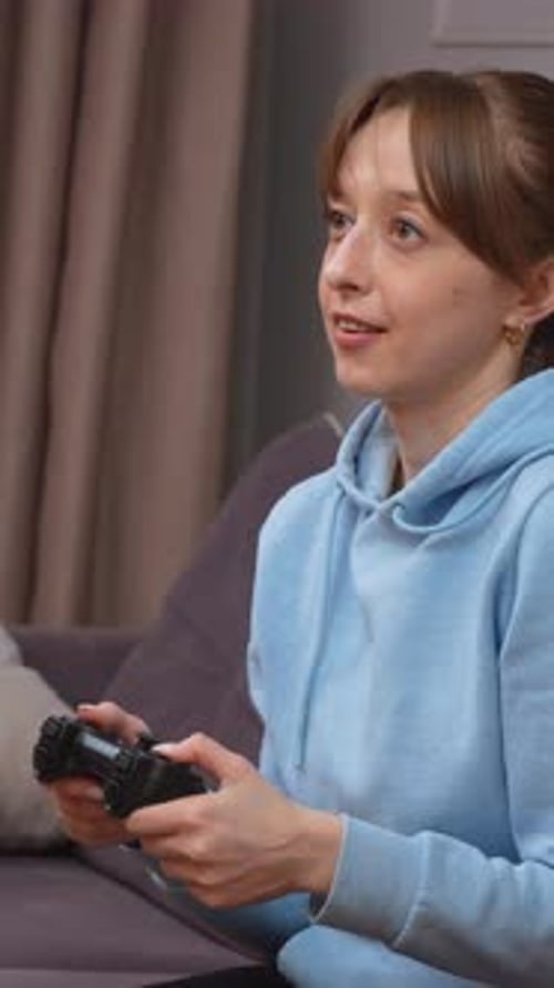 Gamer woman playing videogames on a sofa at home