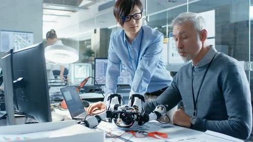 Zwei Ingenieure sprechen, während sie mit dem Roboter arbeiten, seine Reaktionen manipulieren und Daten mit L überprüfen