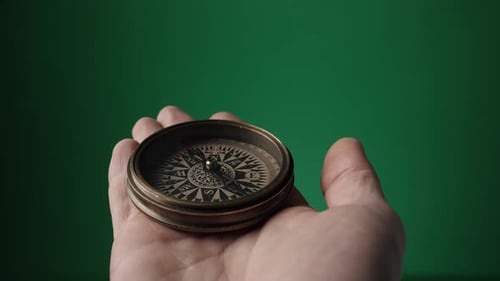Vintage Compass with a Rotating Arrow in a Man's Hand on a Green Screen The Compass Needle Points