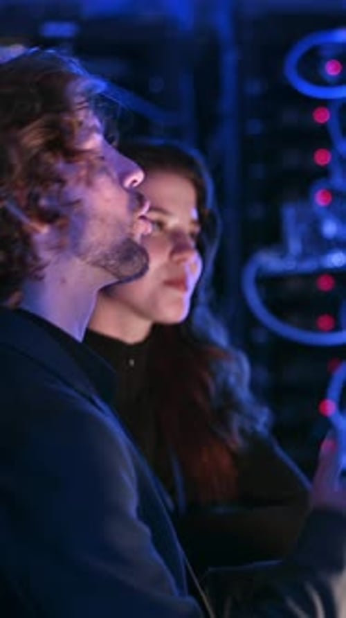 Man and Woman Working in a Dark Server Room