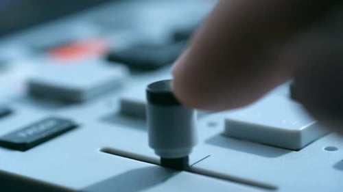 Male Finger Adjusts Sound Levels on Studio Control Panel