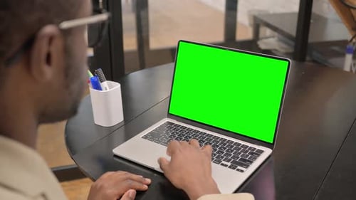 African Man Working on Laptop with Green Screen