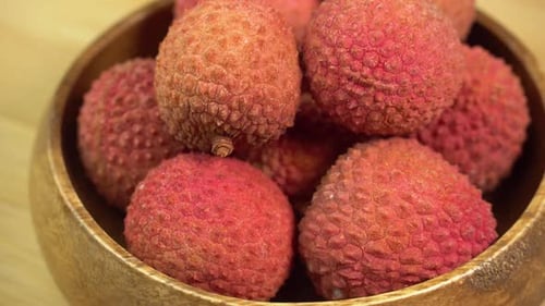 Frische Litschifrüchte in der Schale rotieren in einer Holzschale im Makro. Litschibeeren für die Herstellung
von Limonade
