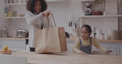 Mother and Daughter Unpacking Groceries in Kitchen