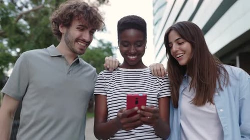 Friends Share Phone Moment While Walking in City