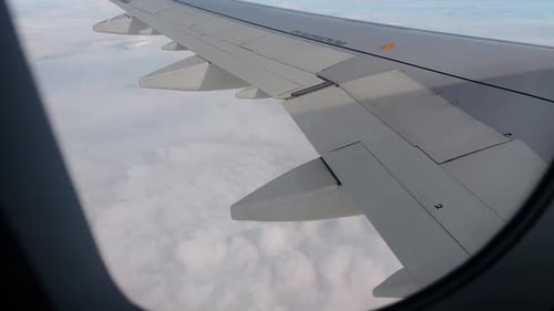 Vue de l'aile de l'avion au-dessus des nuages depuis la fenêtre du passager