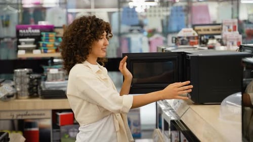 Woman Choosing Microwave Oven in Electronics Store