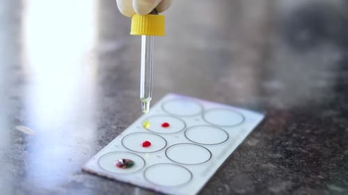 Gros plan de la main du médecin Ajouter des produits chimiques au sang, gouttes sur un panneau de verre pour tester le groupe sanguin à Los Angeles