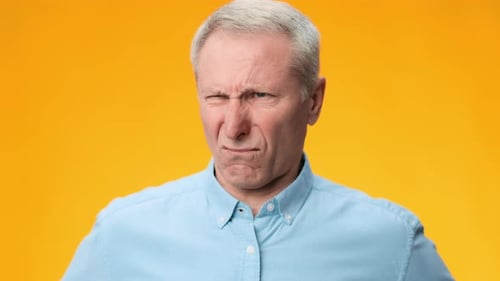 Mann zeigt im Filmmaterial einen lustigen Gesichtsausdruck vor einem leuchtend orangefarbenen Hintergrund