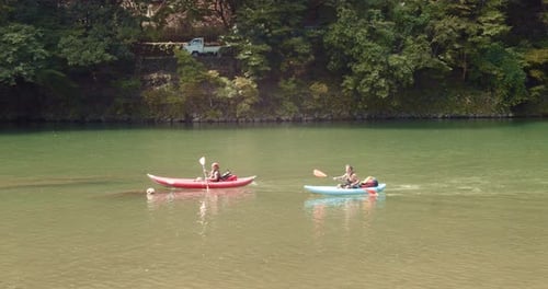 Slide shot of people kayaking down a river in Kyoto, Japan 4K slow motion
