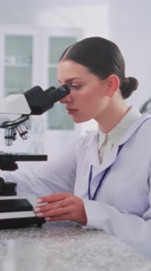 Young woman looking through microscope in science lab