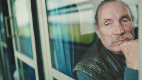 Portrait d'un vieil homme regardant par la fenêtre d'un coupé alors qu'il voyageait en train, vue à travers une vitre