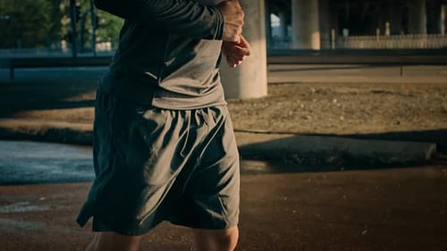 Close Up Shot of an Athletic Muscular Young Man in Sports Outfit Jogging in the Street. He is Runni