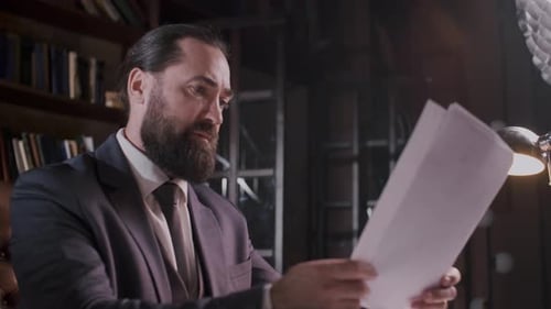 A Businessman is Carefully Examining Documents on His Office Desk with Focus and Concentration