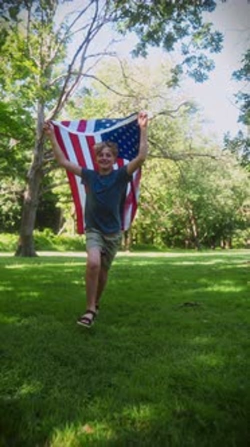 Boy Running with American Flag in Park