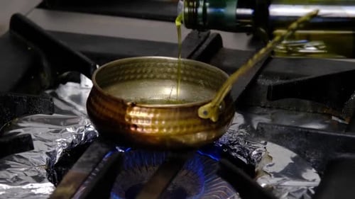 the chef pours oil into the empty pot on the stove
