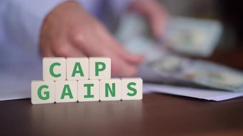 Concept of Capital Gains. Cap gains word with selective focus and person paying on the background.
