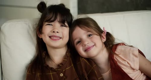 Two Young Girls Smiling Together on Couch