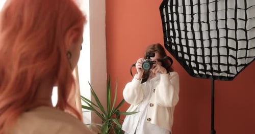 Female Photographer Takes Pictures of a Redhead Model in a Photo Studio