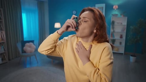 A Woman Uses an Asthma Inhaler During a Coughing Fit Close Up A Woman Using an Inhaler Begins to