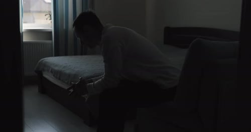 Adult Sitting in Dimly Lit Bedroom