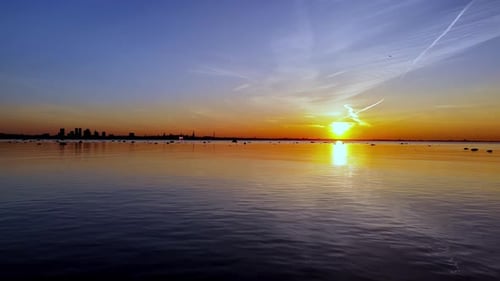 Tallin bei Sonnenuntergang, das über dem Wasser versinkt und eine wunderschöne und ruhige Atmosphäre schafft. Der Himmel ist voll