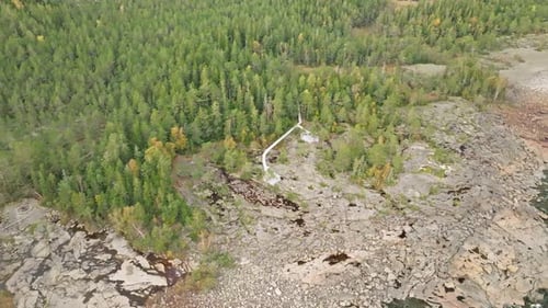 Boardwalk Through Dense Forest Towards The Rocky Shore In Sweden. Aerial Drone Shot