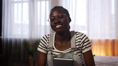 Young Woman Smiling with Notebook in Apartment