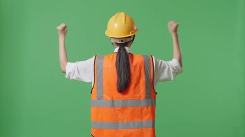 Back View Of A Female Engineer With Safety Helmet Raising Her Hands Celebrating In The Green Screen