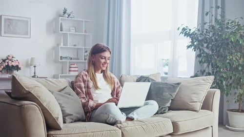Woman Working on Laptop on Couch at Home