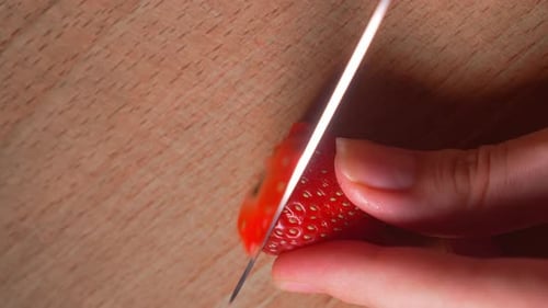 Strawberry Being Sliced on a Cutting Board