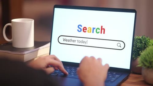 Hands Typing Weather Search on Laptop