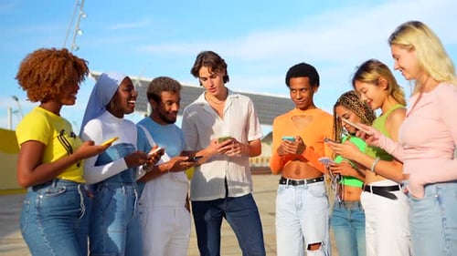 Friends Laughing While Using Cell Phones Outdoors