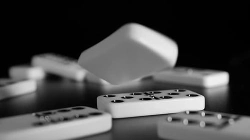 White domino dice fall on a black background. Slow motion
