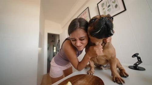 Woman Cuddling French Bulldog in Kitchen at Home