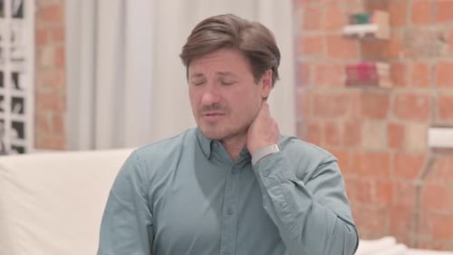 Man Rubbing Stiff Neck in Indoor Setting