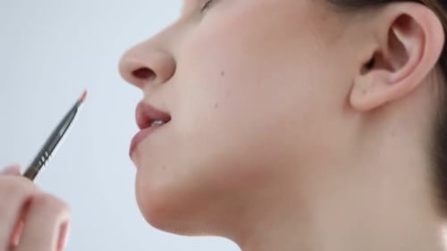 Artista fazendo maquiagem bonita no rosto de uma mulher em ambientes fechados, de perto