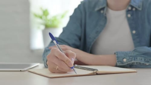Gros plan d'une jeune femme écrivant sur papier au bureau
