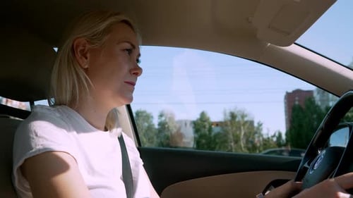 Blonde woman in car confidently concentrated calmly driving around city