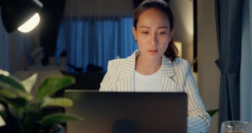 Woman Works on Laptop at Night in Home Office
