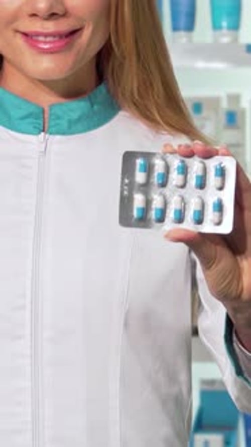 Woman Smiling Holding Pack of Blue and White Pills