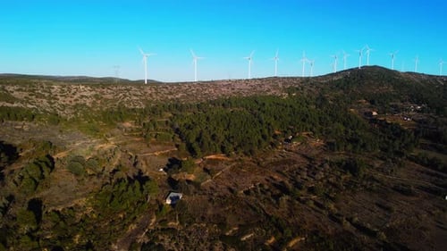 Aerial drone footage of a wind turbines on mountain ridges generating renewable energy.