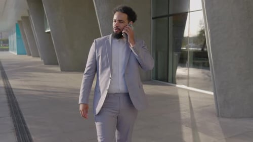 A Businessman Dressed in a Stylish Suit is Actively Engaged in a Conversation on His Phone