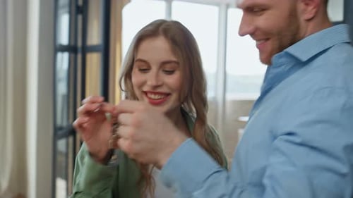 Couple Smiling Holding Keys Inside New Home