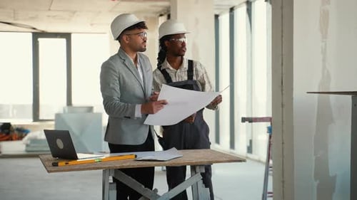 Architect and Construction Worker Discussing Blueprints in Building