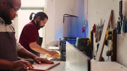 Équipe de menuisiers dans un atelier d'assemblage utilisant du papier abrasif et une moulure à broche